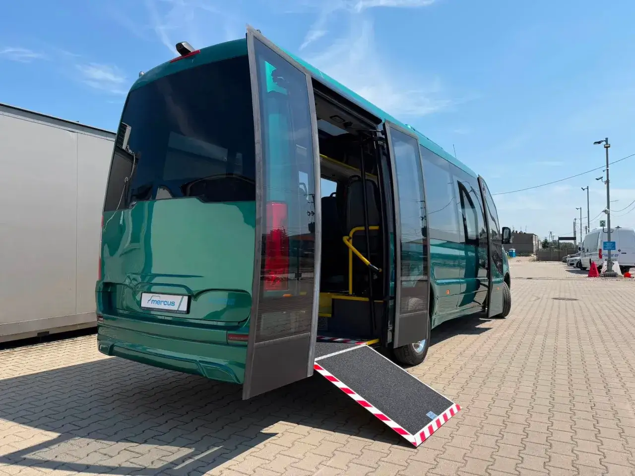 Zielony bus z rozłożoną rampą ułatwia przewóz wahadłowy osób.