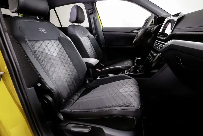 Interni sportivi con sedili in tessuto grigio a rombi e logo R. Console centrale e cruscotto neri.