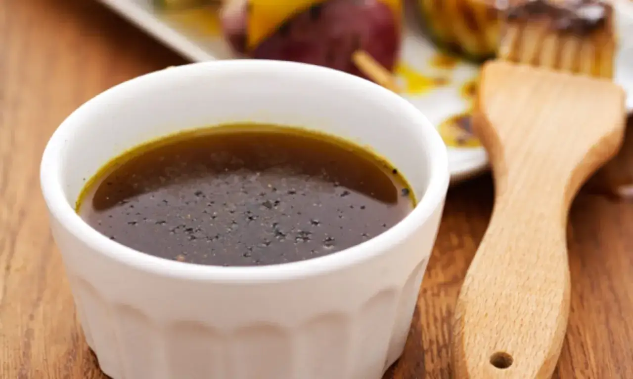 En skål med mörk marinad, perfekt för ditt nästa grillolja recept. En pensel ligger bredvid, redo att applicera smak.