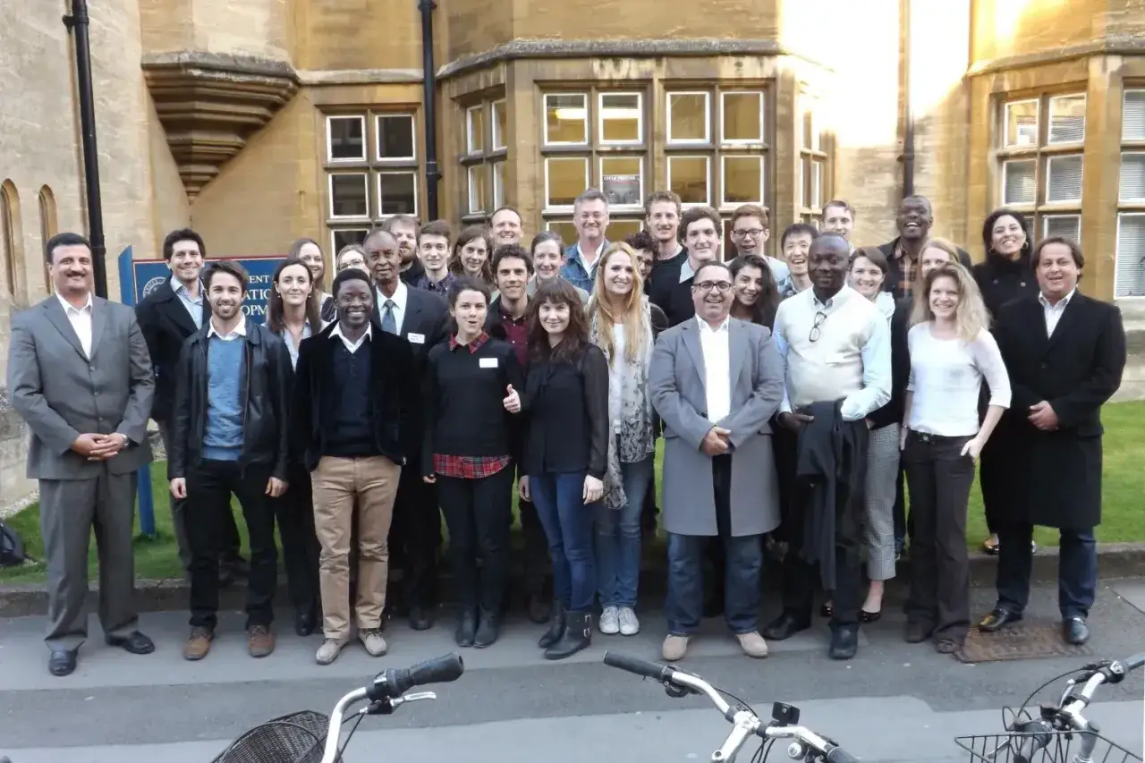 Group photo of diverse professionals after advanced negotiation skills training, smiling outside a historic building.