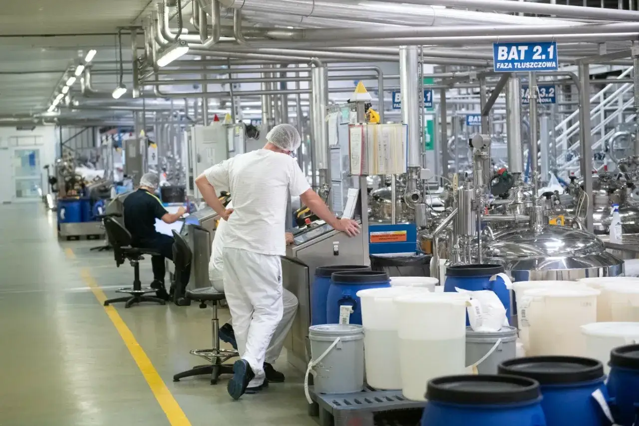 Praca w Niemczech z zakwaterowaniem i wyżywieniem czeka na Ciebie! Pracownicy w białych strojach nadzorują proces produkcyjny w nowoczesnej fabryce.