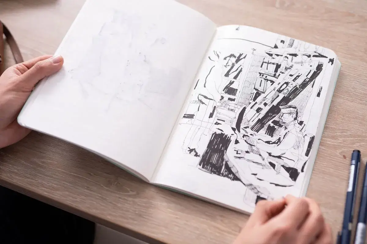 Un carnet ouvert montre un dessin au trait d'une scène intérieure animée, un objet dessin facile.