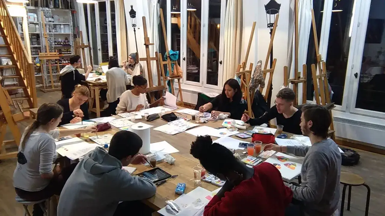 Des &eacute;l&egrave;ves concentr&eacute;s dans une &eacute;cole d'art, travaillant sur leurs cr&eacute;ations &agrave; une grande table.
