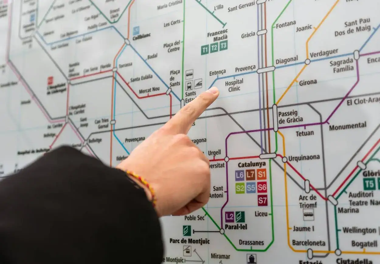Palec na mapie metra w Barcelonie, wskazujący stację Hospital Clínic. Planujesz podróż z Barcelona El Prat?