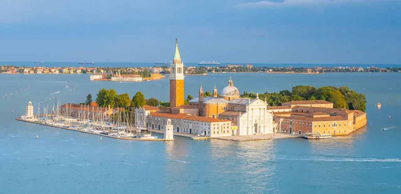 Isola di San Giorgio Maggiore a Venezia, con il suo campanile e la chiesa, circondata dal mare e da barche. Venezia è un'isola.