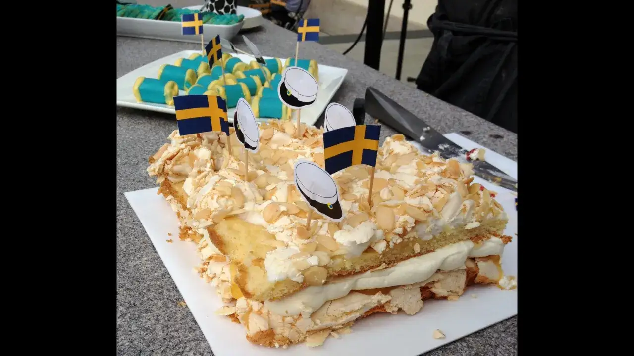 En generös pinocchiotårta med lemoncurd, toppad med maräng och mandelspån. Svenska flaggor och studentmössor pryder tårtan.