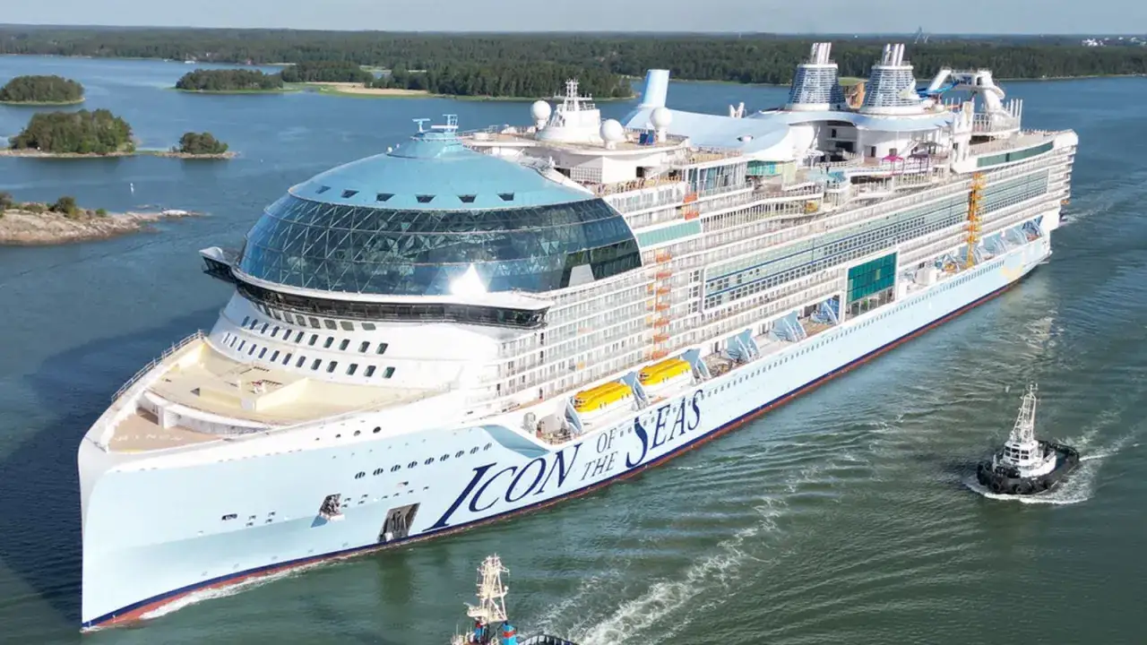 Największy statek wycieczkowy, Icon of the Seas, sunie po wodzie, otoczony zielonymi wyspami.