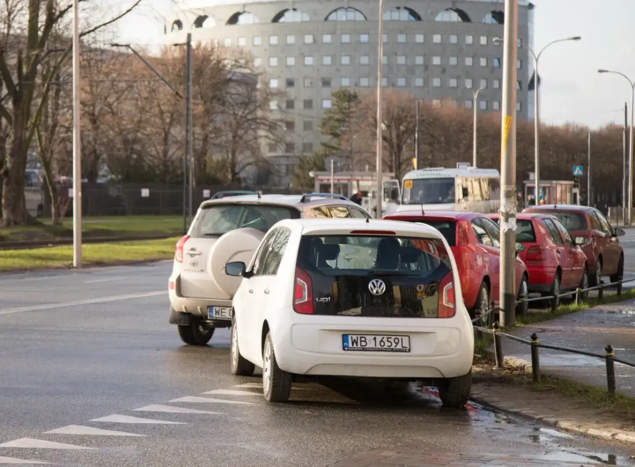 Biały Volkswagen Up! zaparkowany na pasach. Zastanawiasz się, ile metrów od skrzyżowania można parkować?