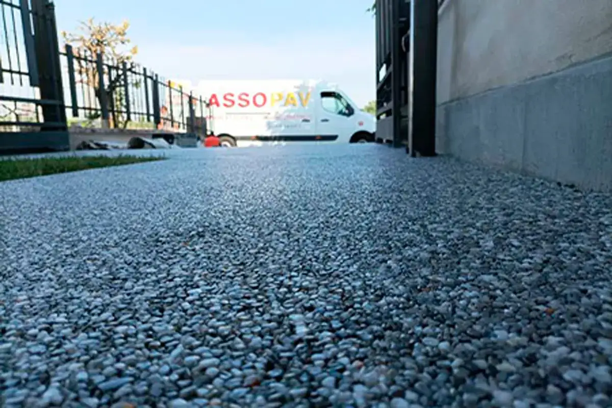 Pavimentazione drenante per parcheggio con ghiaia colorata. Un furgone bianco con logo 