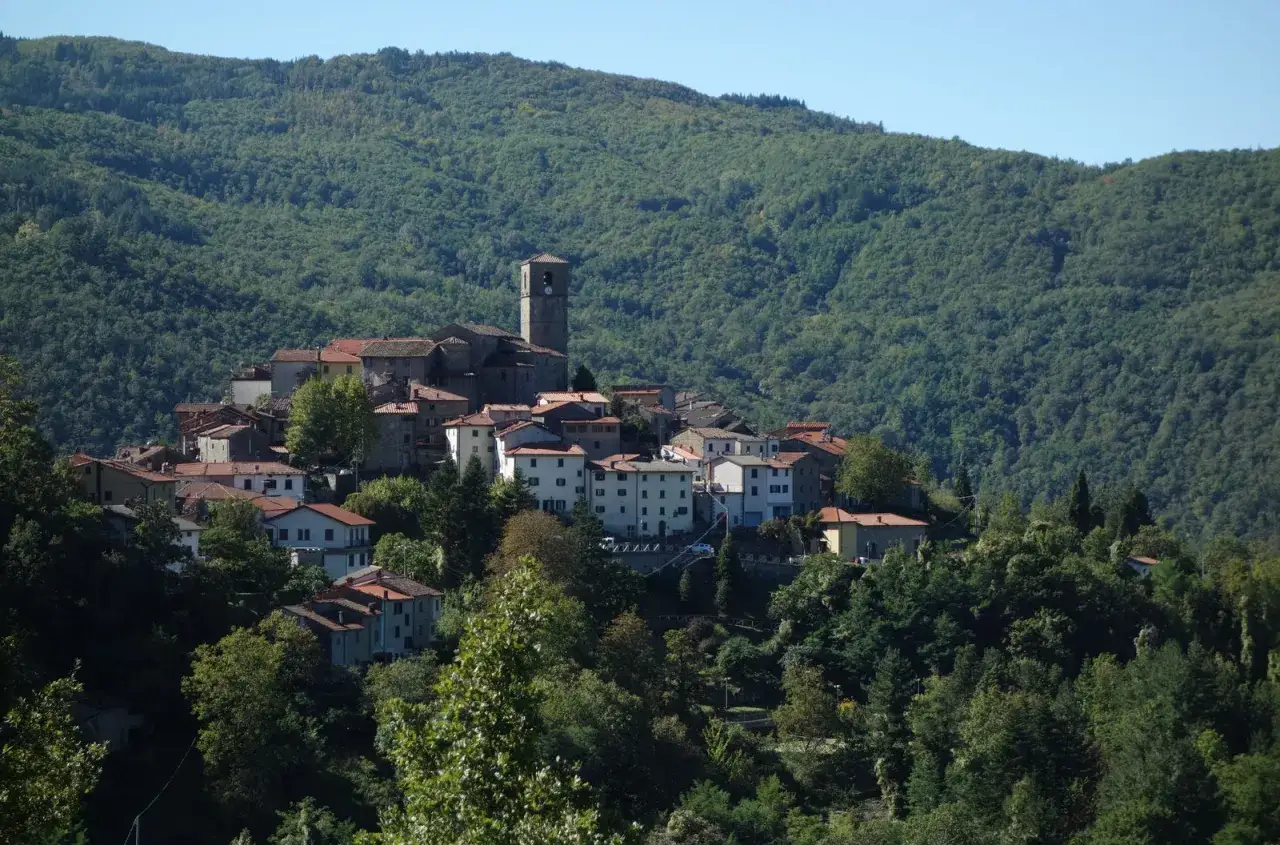 Borgo medievale di San Marcello Pistoiese, con case in pietra e tetti rossi, incastonato tra colline boscose.