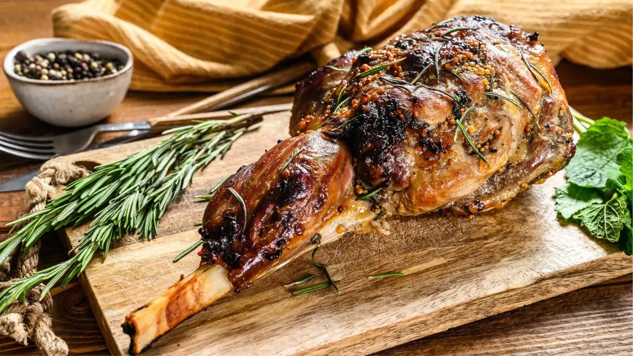 Paletilla de cordero al horno, dorada y jugosa, con romero y granos de pimienta. Lista para disfrutar.