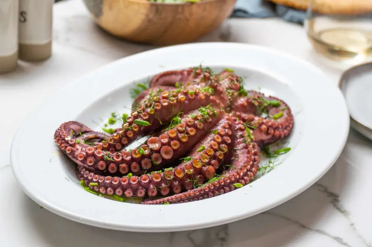 Un poulpe entier, cuit et garni d'herbes fraîches, prêt à être dégusté. Une recette de poulpe simple et savoureuse.