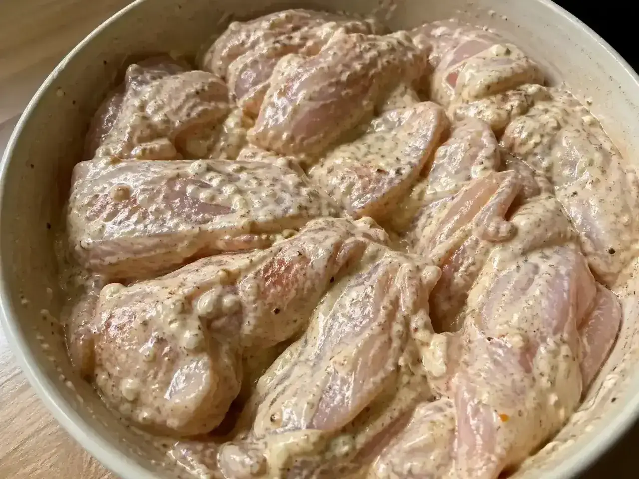 Rå kycklingbitar i en krämig marinad, redo att tillagas. En härlig marinad kyckling för en smakrik måltid.