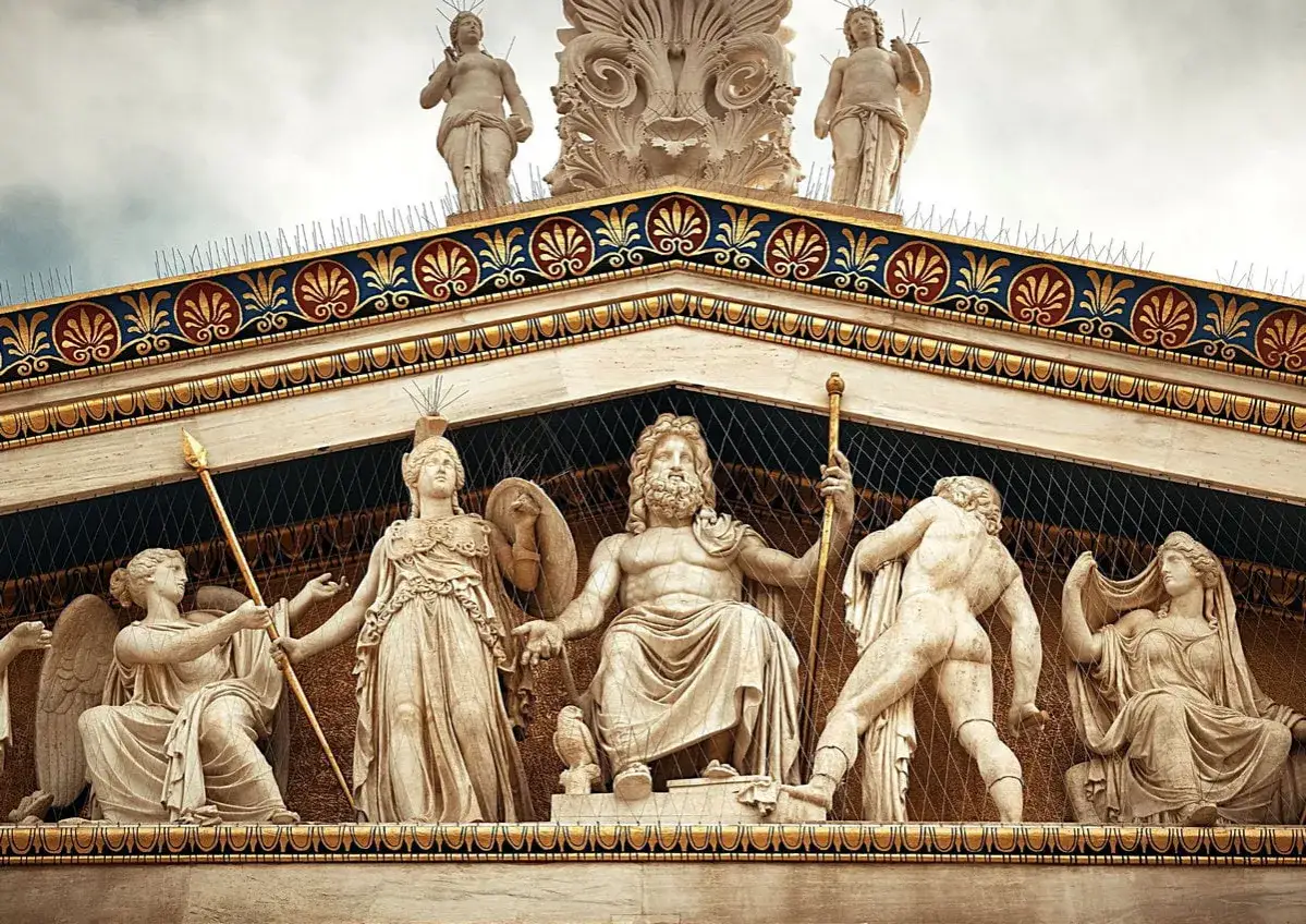 Kamienna rzeźba przedstawia bogów greckich: Zeusa siedzącego pośrodku, Atenę z włócznią i tarczą, a także inne postacie mitologiczne.