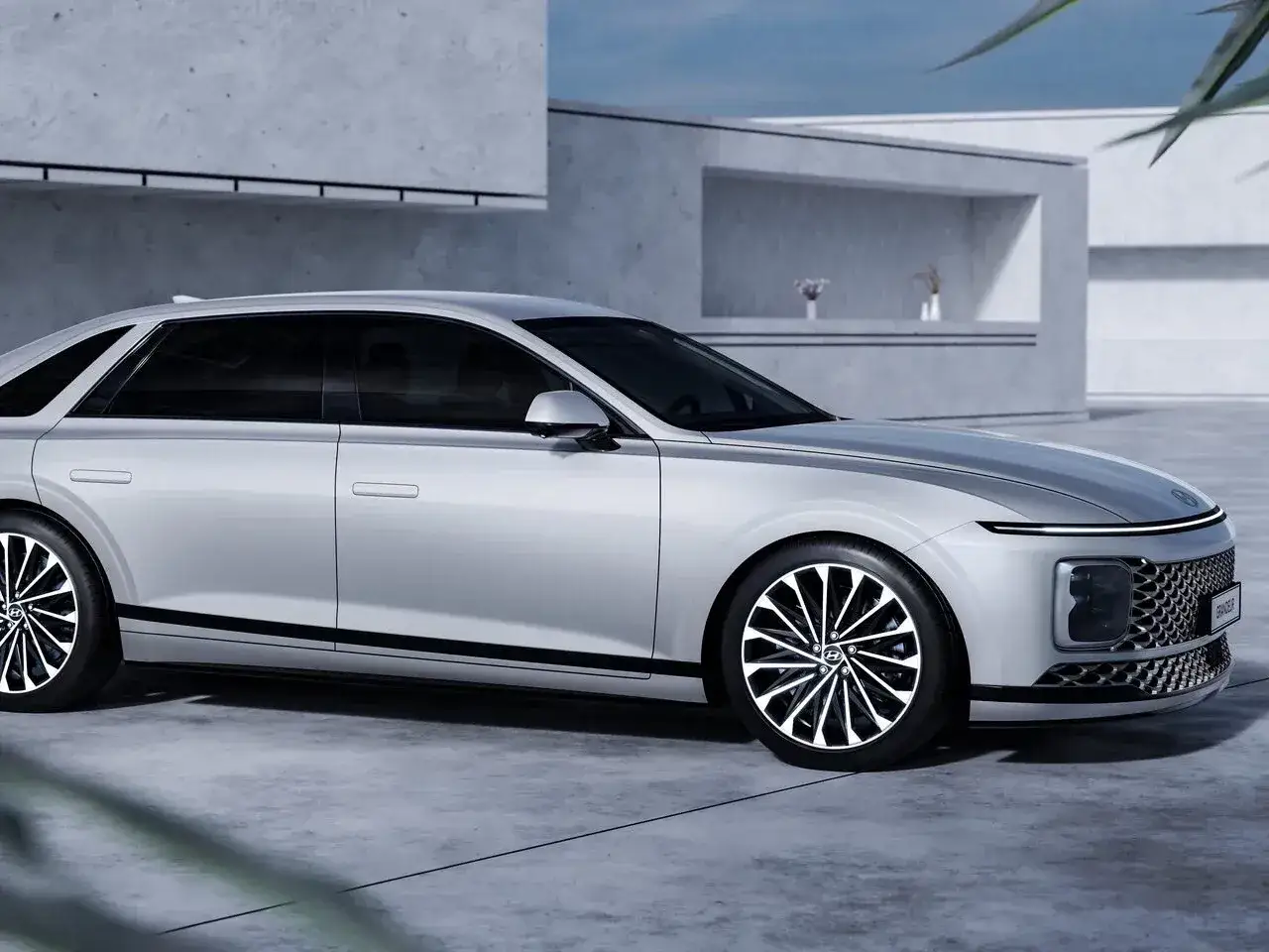 Elegancki, srebrny Hyundai Grandeur z nowoczesnym designem, zaparkowany przed minimalistycznym budynkiem.