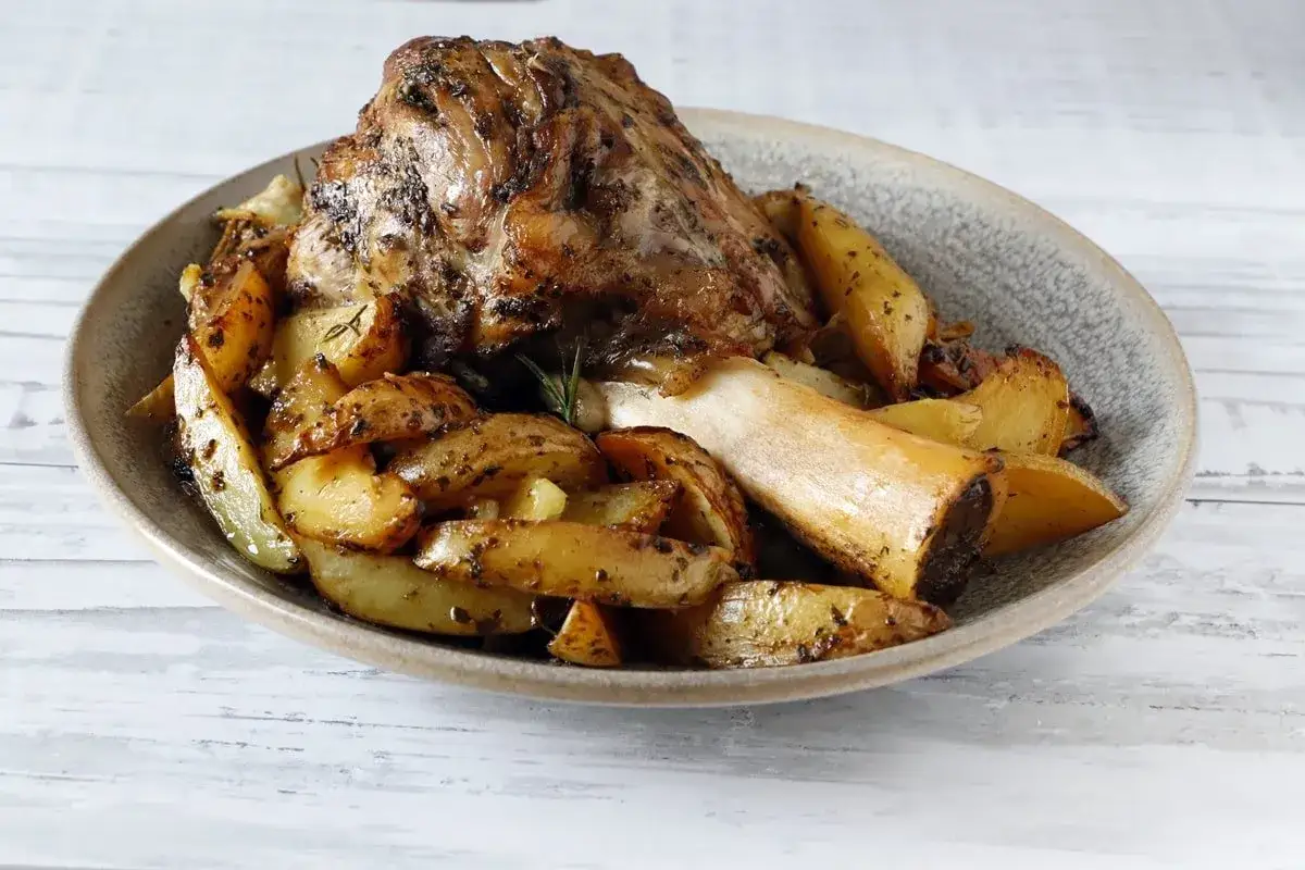 Stinco di vitello al forno, succulento e dorato, servito con patate arrosto speziate. Un piatto che profuma di casa.