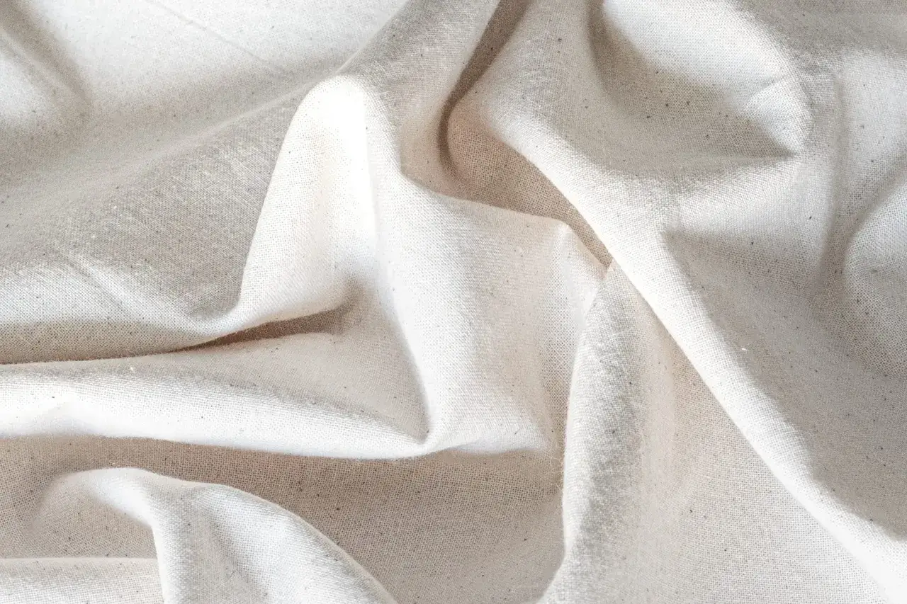Soft, natural muslin cotton fabric with subtle texture and gentle folds, perfect for crafting or baby swaddles.