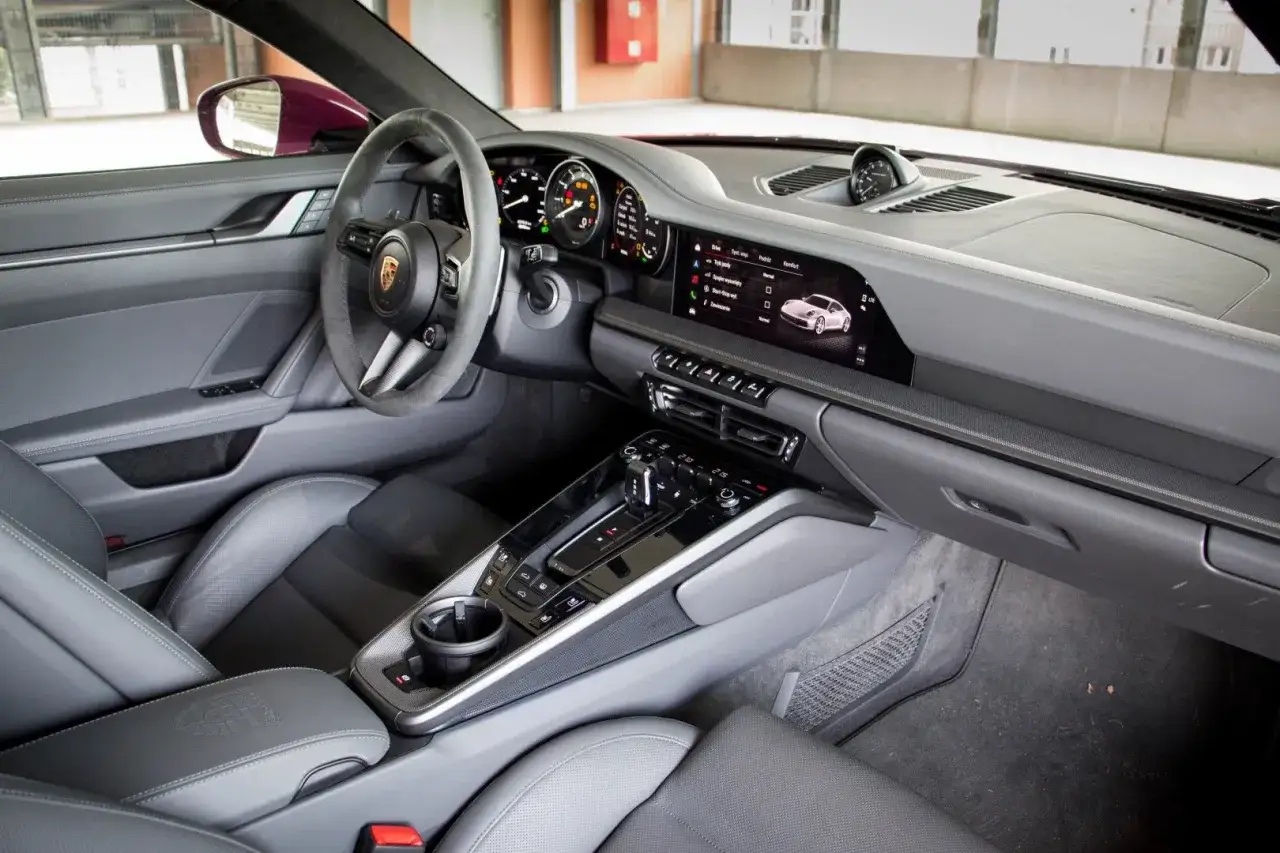 Wnętrze Porsche 911 Carrera 4S: skórzana tapicerka, cyfrowe zegary, dotykowy ekran multimediów i sportowa kierownica.