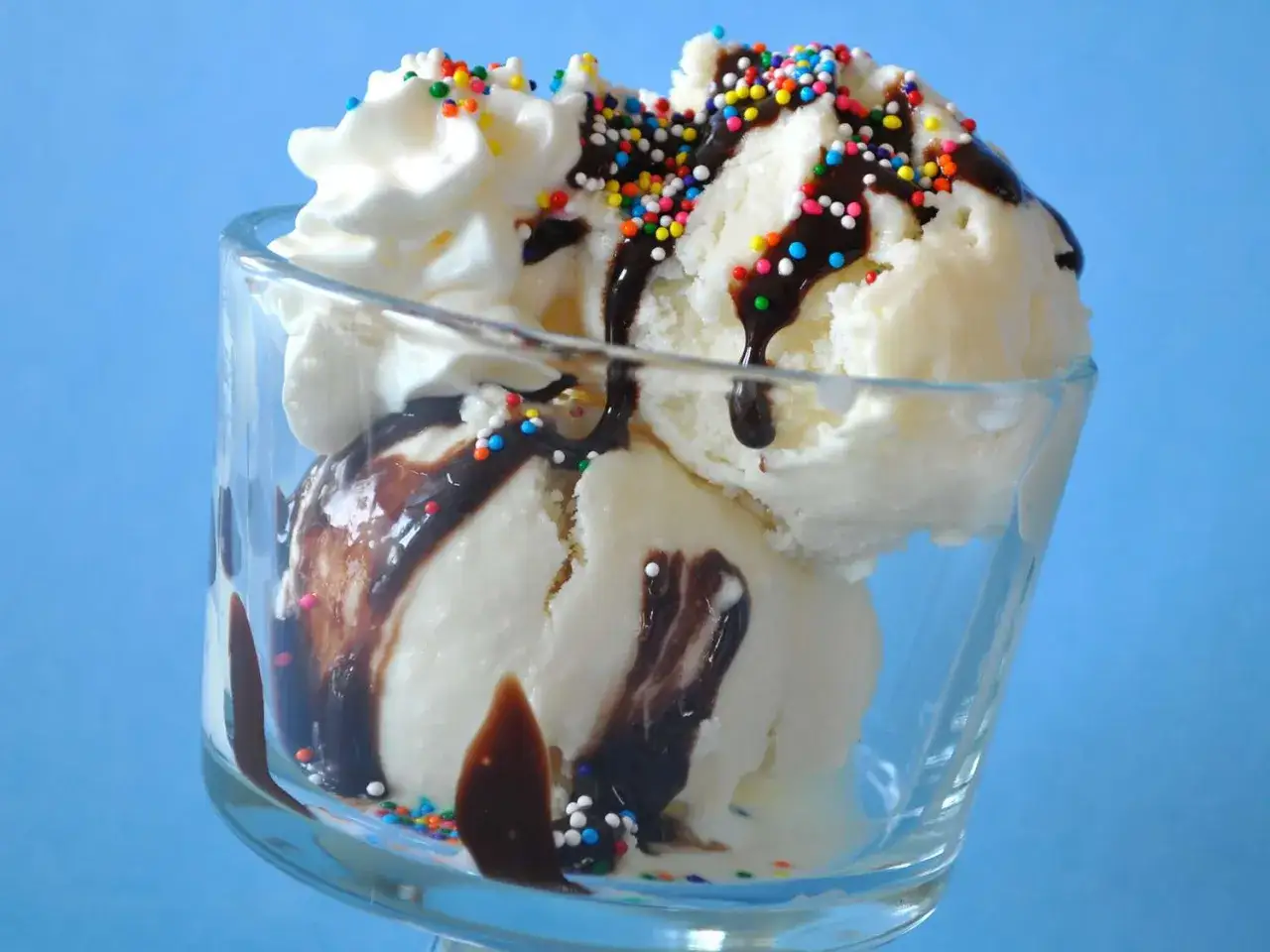 Ein Eisbecher mit Vanilleeis, Schokoladensauce und bunten Streuseln. Das ist vollrahm, ein Genuss für alle Sinne.
