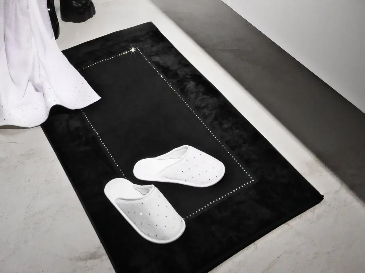 Schwarzer Badvorleger mit funkelnden Details und wei&szlig;en Pantoffeln. Perfekt zum Waschen und f&uuml;r ein luxuri&ouml;ses Badezimmer.