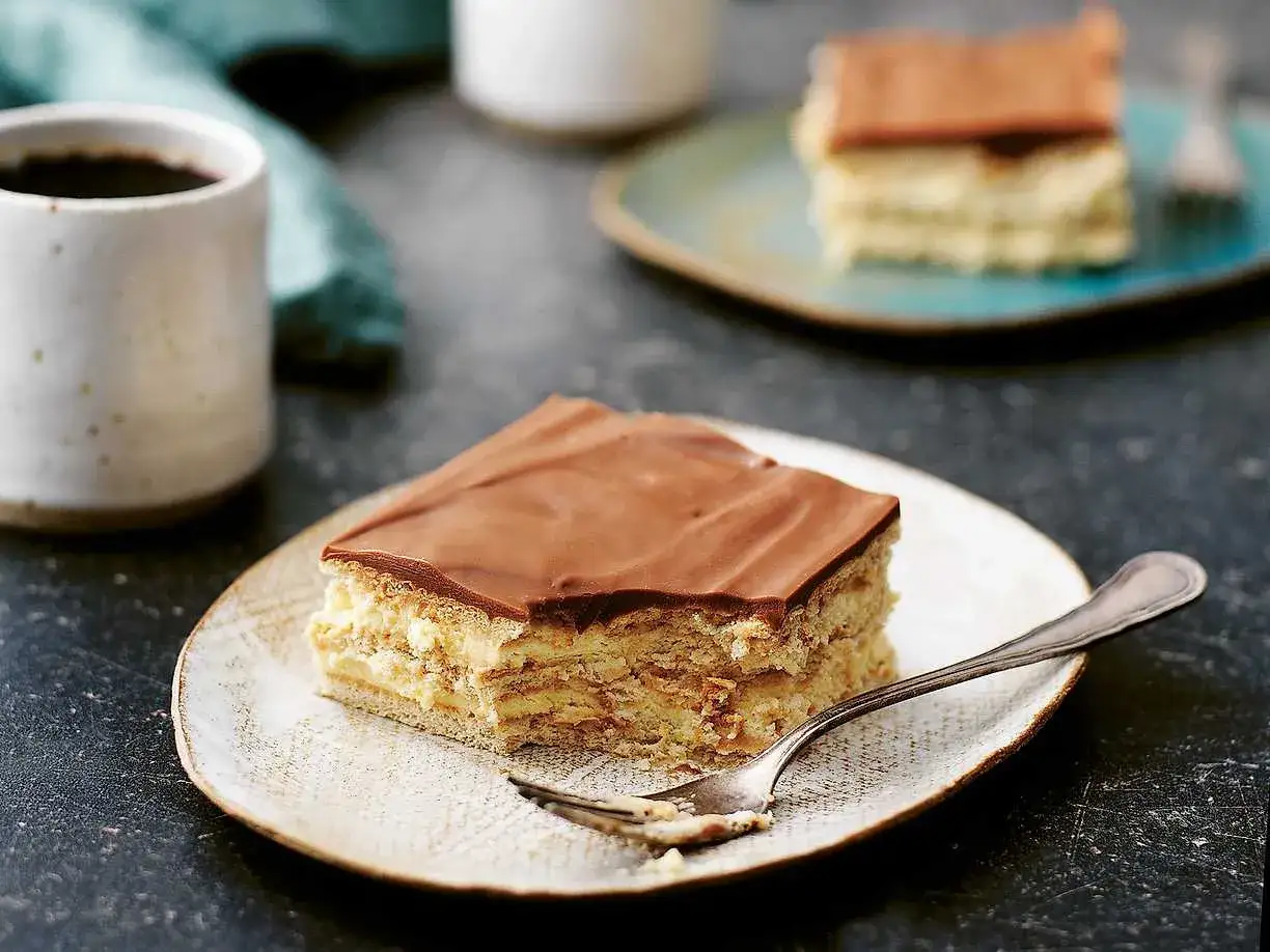 En bit chokladglaserad tårta med lager av kex och kräm, perfekt för ett mariekex recept. En gaffel ligger på tallriken.