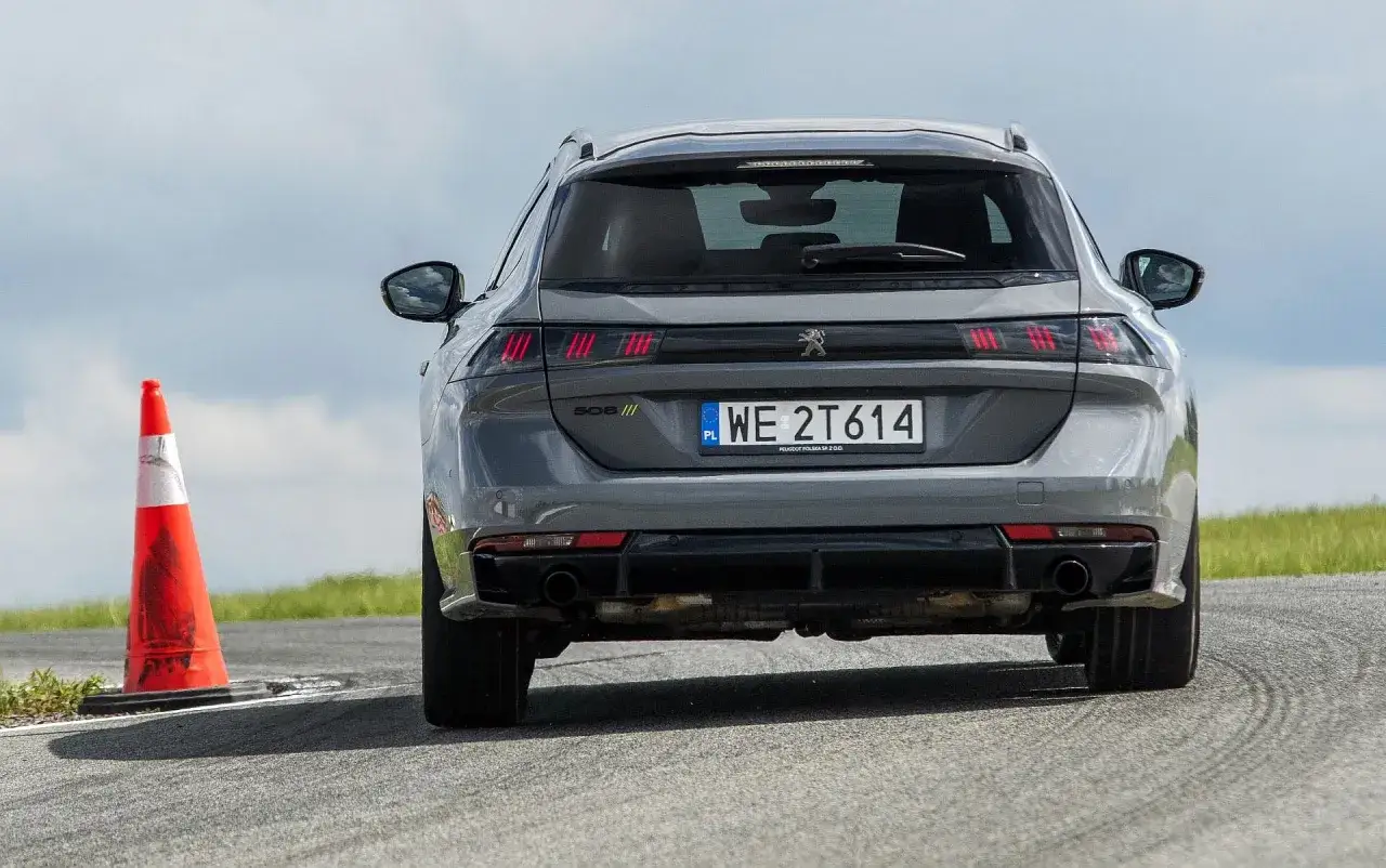 Szary Peugeot 508 SW na torze, obok pomarańczowy pachołek. Test opon letnich w akcji.