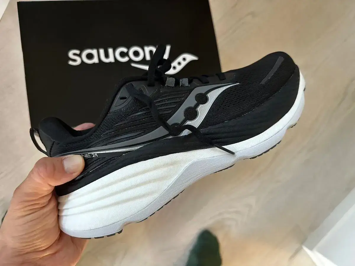 En svart Saucony löparsko med vit sula, som visar en skillnad på dam och herrskor.