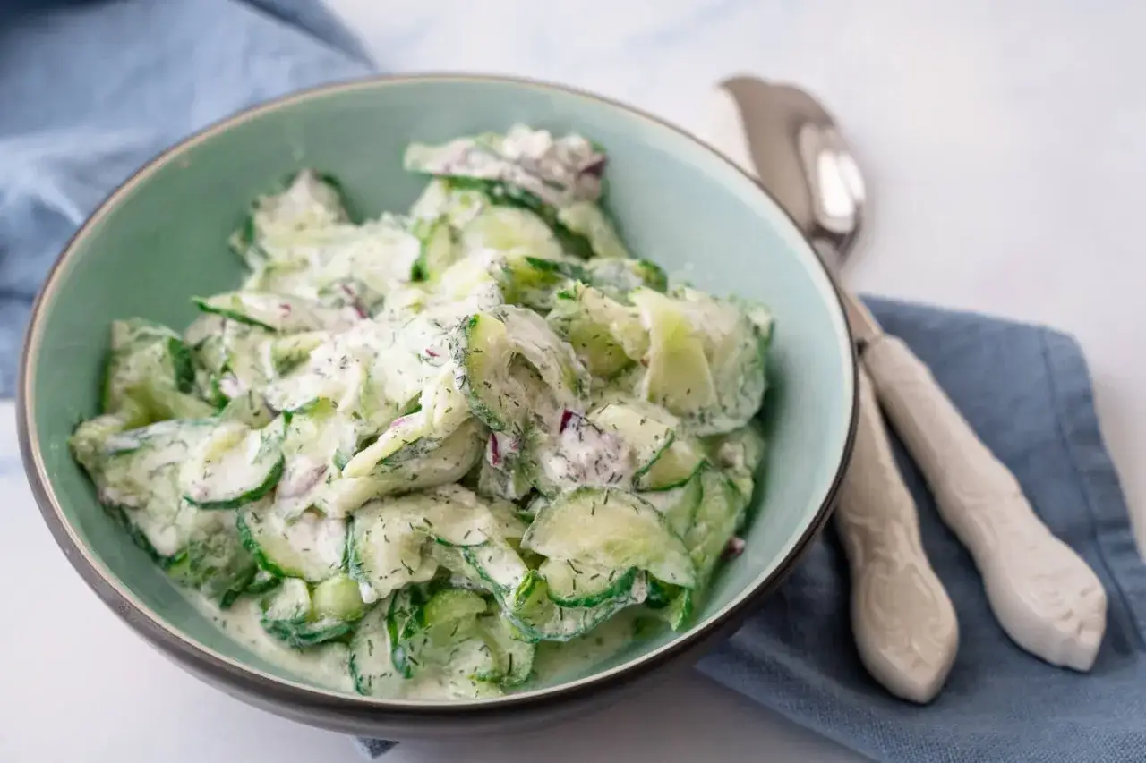 Frischer gurkensalat mit saurer sahne und Dill, garniert mit roten Zwiebeln, in einer Schüssel serviert.