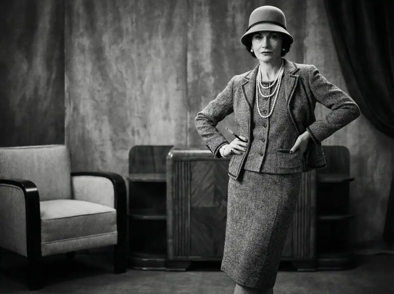 Coco Chanel, icona di stile, incarna il vero **chanel significato**: eleganza senza tempo nel suo iconico tailleur e perle.
