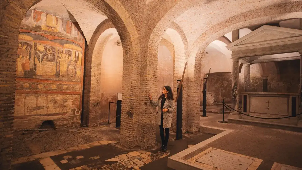 A woman explores ancient frescoes and a marble altar in one of Rome's historic churches, revealing the city's rich past.