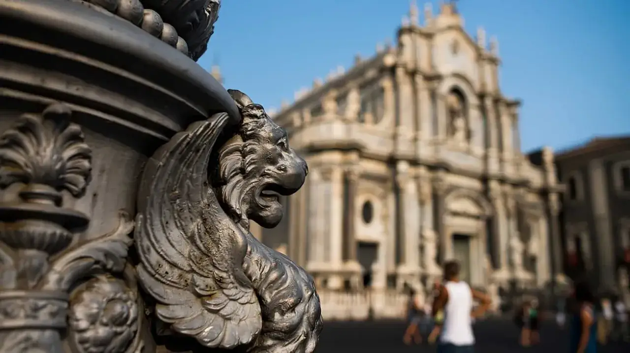 Détail d'une gargouille en métal devant la cathédrale de Catania, Sicile. Le soleil brille sur la place animée.