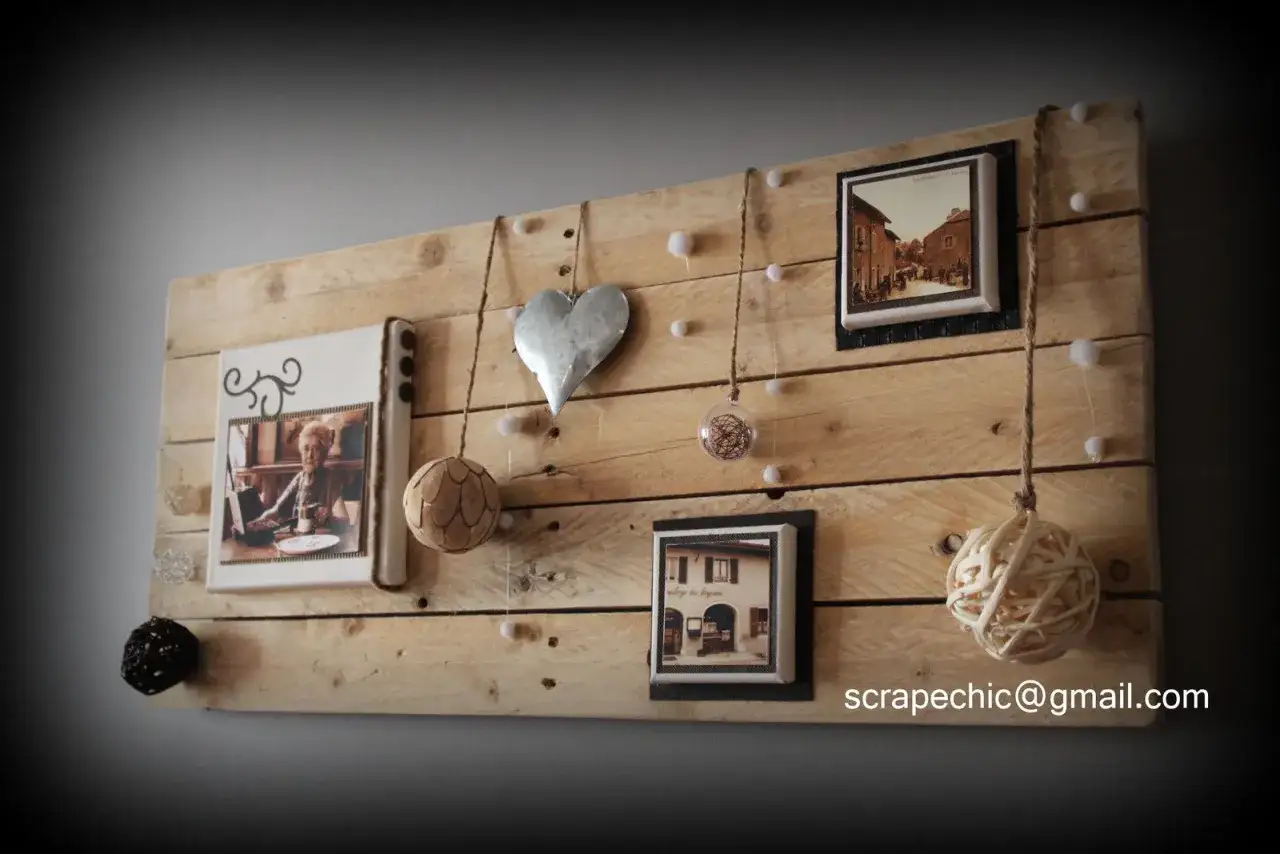 Id&eacute;e pour fabriquer un cadre photo en bois de palette : un panneau rustique orn&eacute; de photos, d'un c&oelig;ur en m&eacute;tal et de d&eacute;corations suspendues.