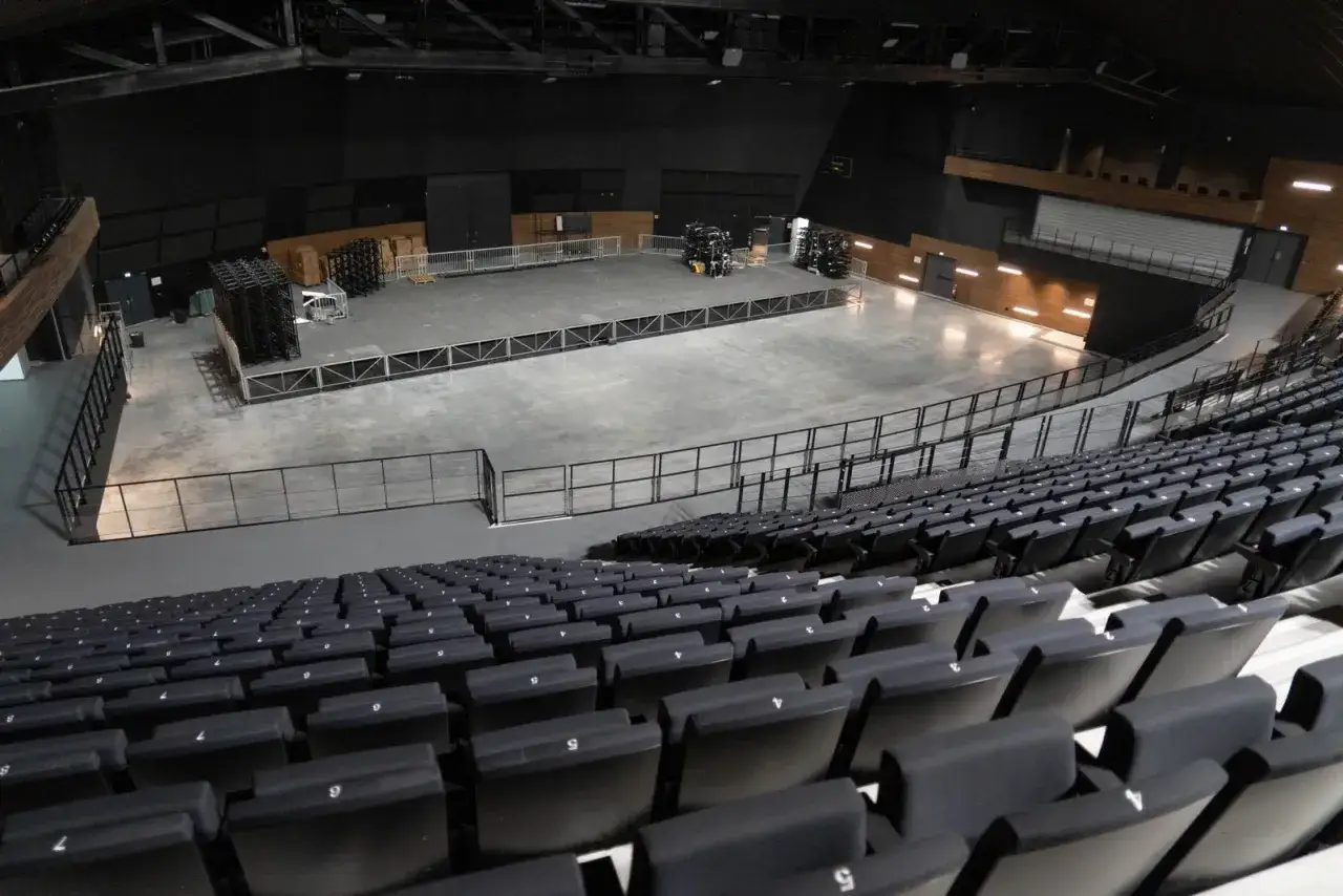 Vue d'une scène vide dans une arena parisienne, prête pour un spectacle. Les sièges sont rangés, attendant le public.