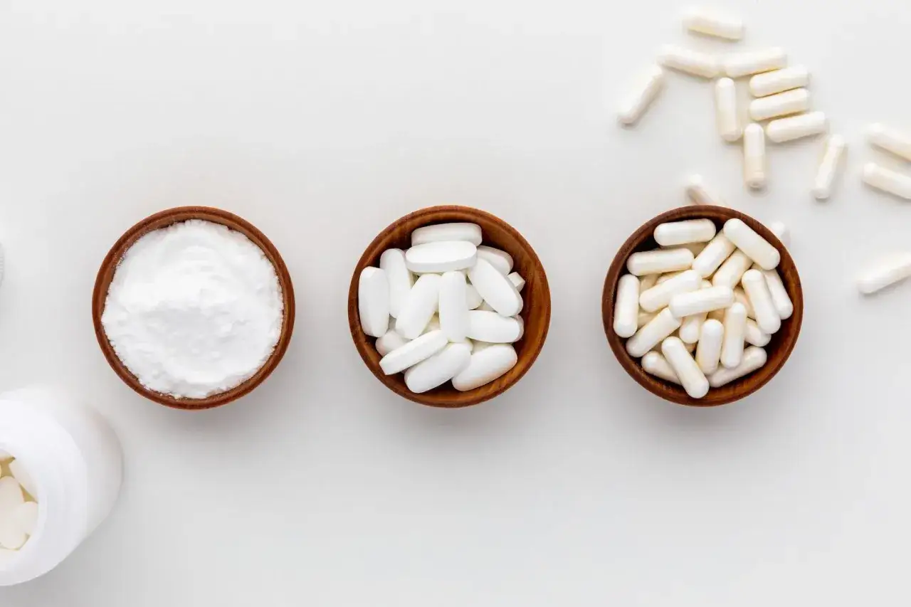 Tre ciotole di legno con polvere bianca, compresse e capsule. Forse integratori di n acetilcisteina.