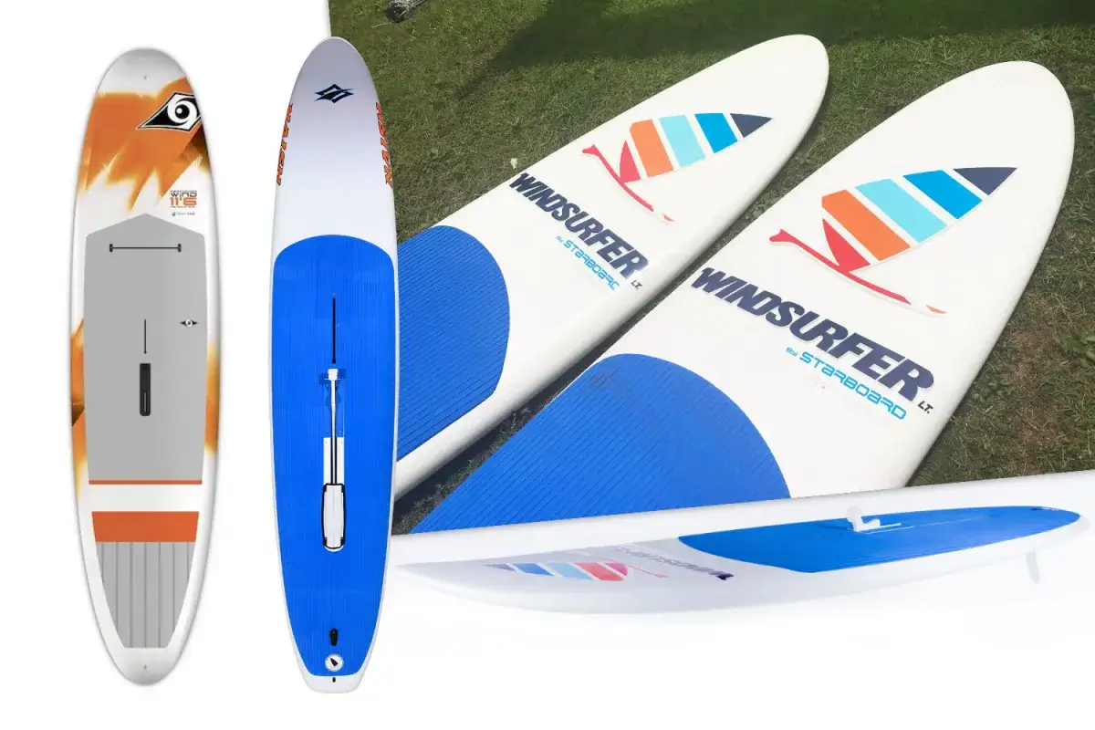 Mehrere Windsurfboards, ideal für Anfänger, liegen auf Gras. Eines ist weiß mit orangefarbenen Akzenten, die anderen sind weiß mit blauen und bunten Segel-Logos.