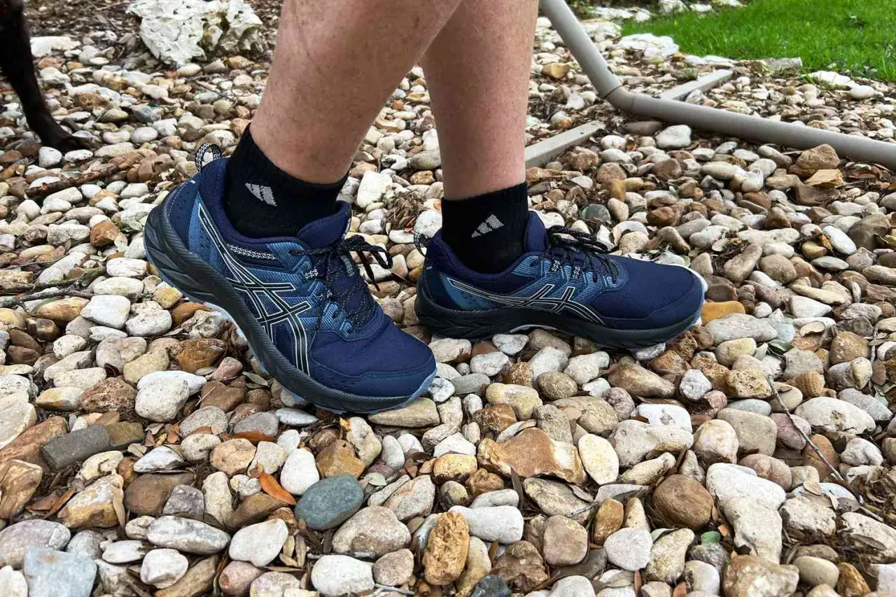 Blaue Asics Schuhe auf Steinen, ideal für Läufer mit Plantarfasziitis, die Komfort und Halt suchen.