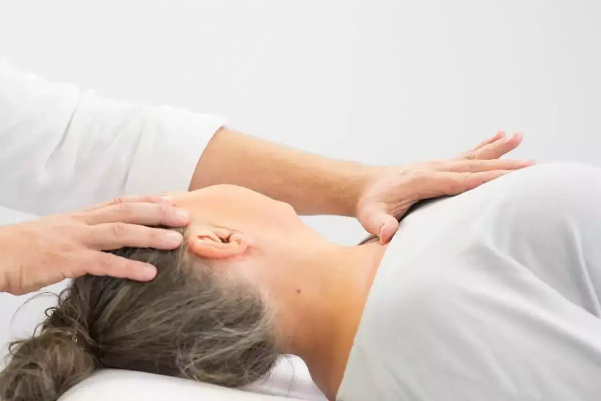 Delikatne dłonie terapeuty wykonują terapię czaszkowo krzyżową, przynosząc ulgę i relaks.