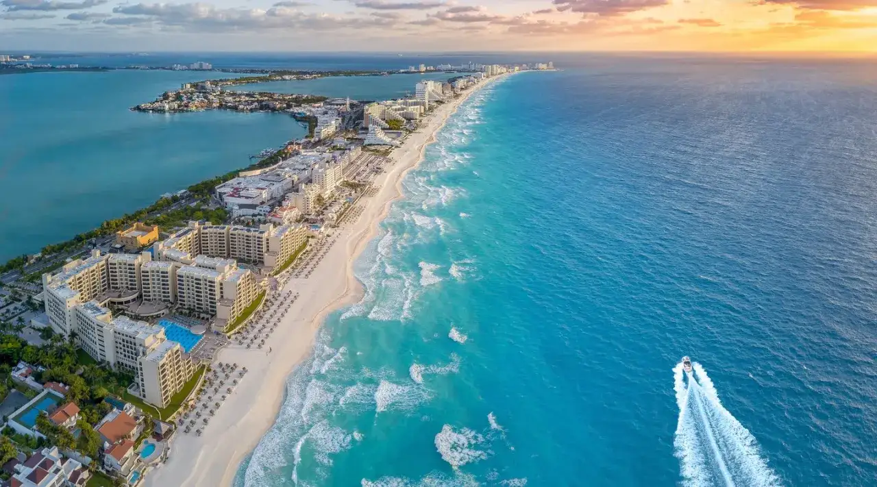 Vista a&eacute;rea de Canc&uacute;n, M&eacute;xico. Hoteles, playa de arena blanca y mar turquesa invitan a viajar a M&eacute;xico. Una lancha surca las olas.