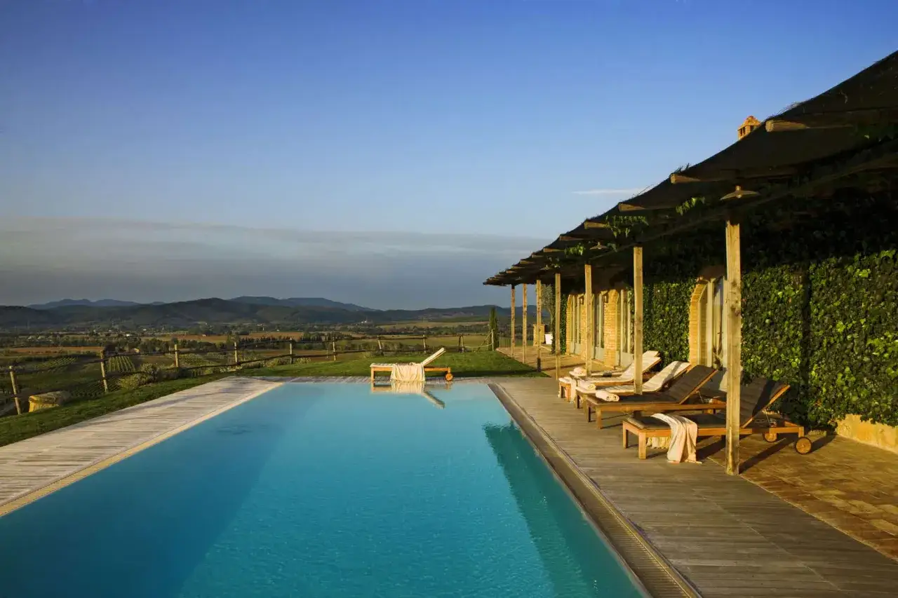 Piscina panoramica con lettini e vista sulle colline toscane, un perfetto wine resort per rilassarsi.