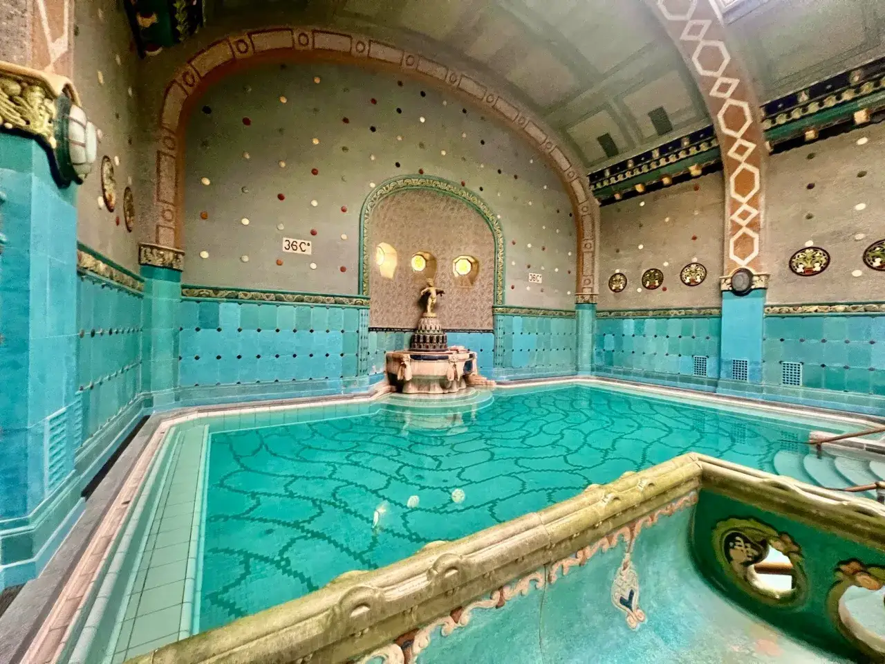 Ett vackert, turkost bad i ett Budapest spa med utsmyckade v&auml;ggar och tak.