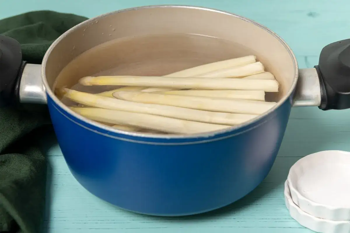 Espárragos blancos en una olla azul con agua hirviendo, listos para cocer.
