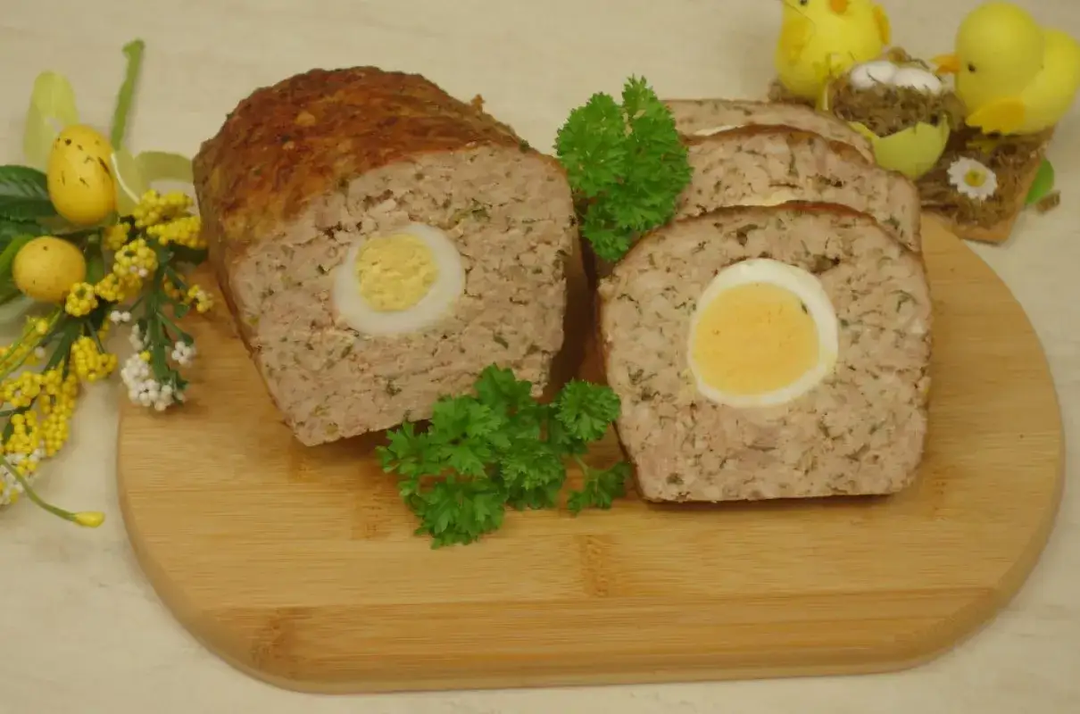 Pieczeń rzymska przepis: aromatyczna rolada mięsna z jajkiem w środku, ozdobiona natką pietruszki i wielkanocnymi kurczaczkami.