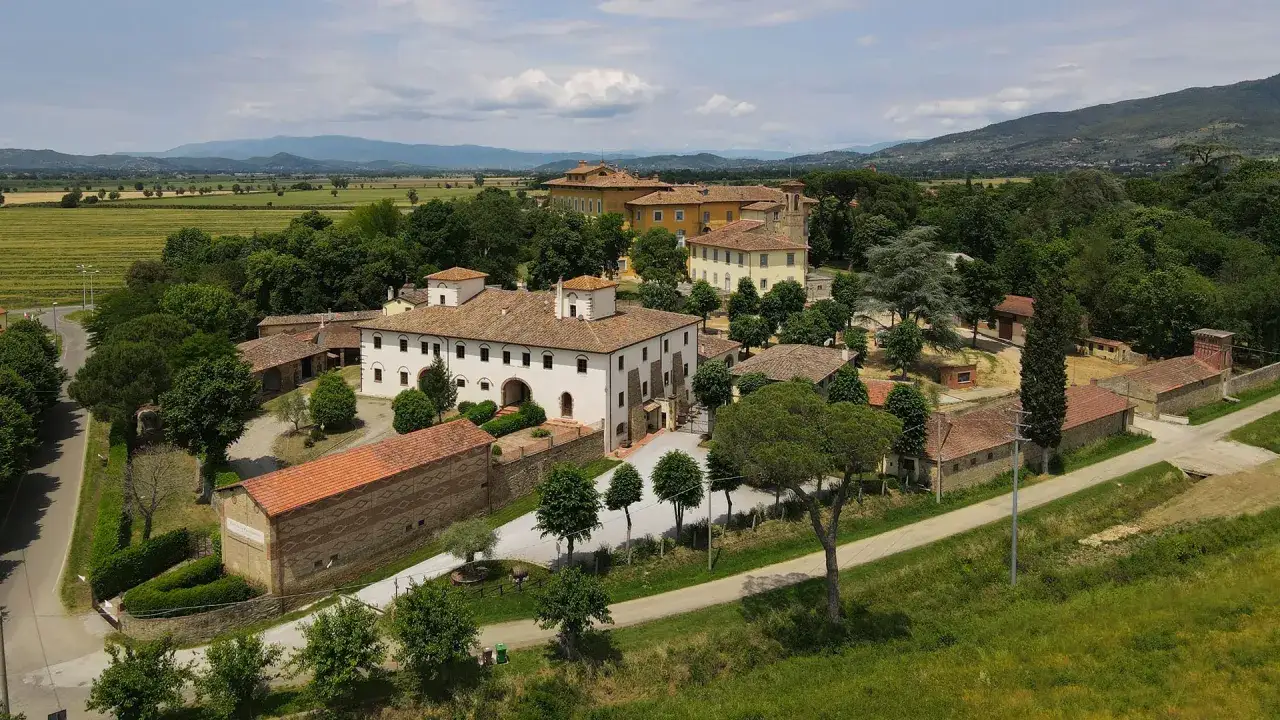 La tenuta Frassineto, con i suoi casali in pietra e le ville signorili, si estende tra verdi colline e campi coltivati, un'oasi di pace toscana.