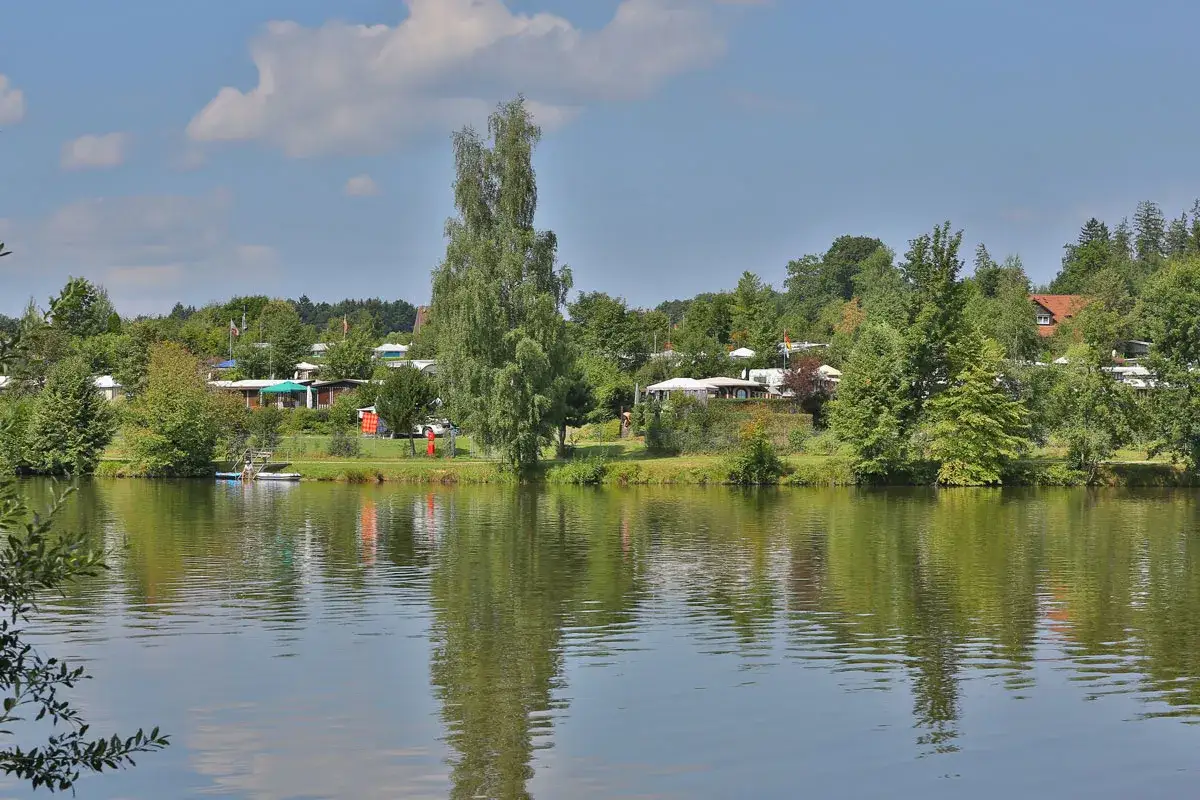 Idyllischer Blick auf den Ellwangen See mit einem Campingplatz im Hintergrund.