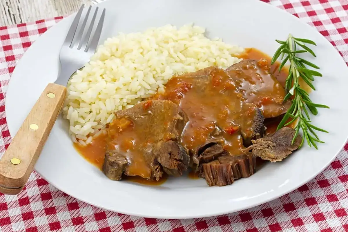 Plato de lengua de ternera en salsa con arroz blanco y romero. Un manjar casero listo para disfrutar.