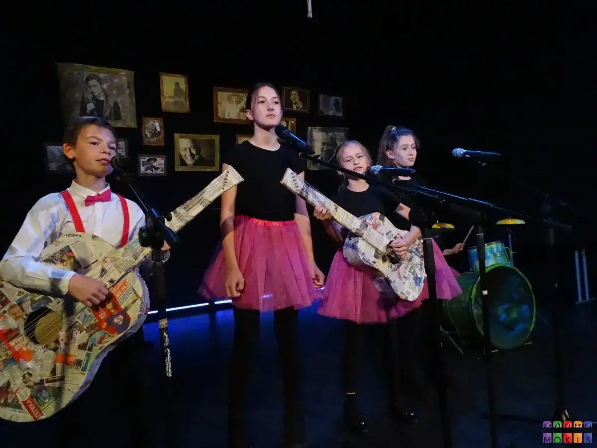Dzieci grają na gitarach z gazet, śpiewając stare piosenki z dzieciństwa.