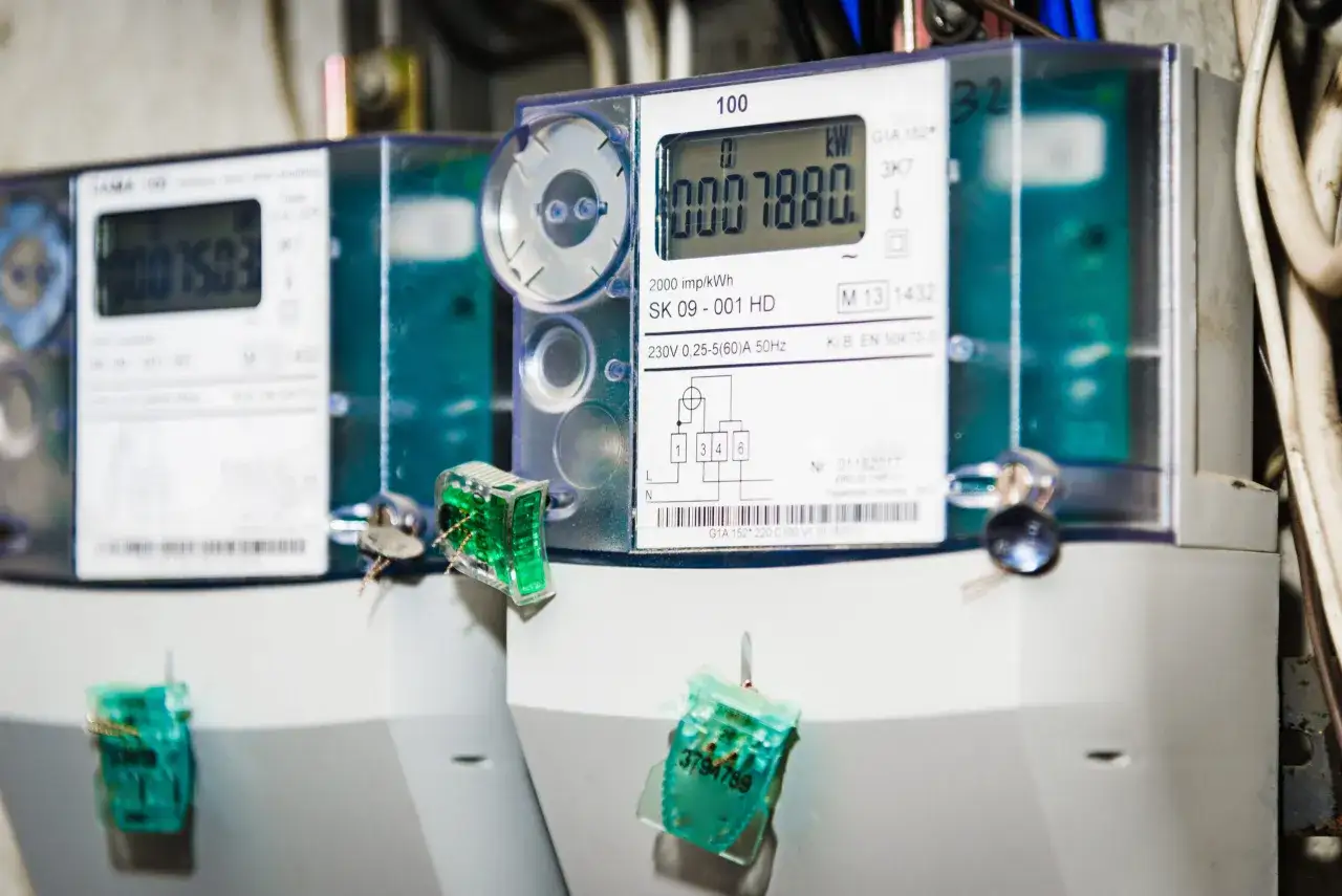 Dwa liczniki energii elektrycznej. Na jednym z nich widoczny odczyt 0007880 kWh. Zielone plomby zabezpieczające.
