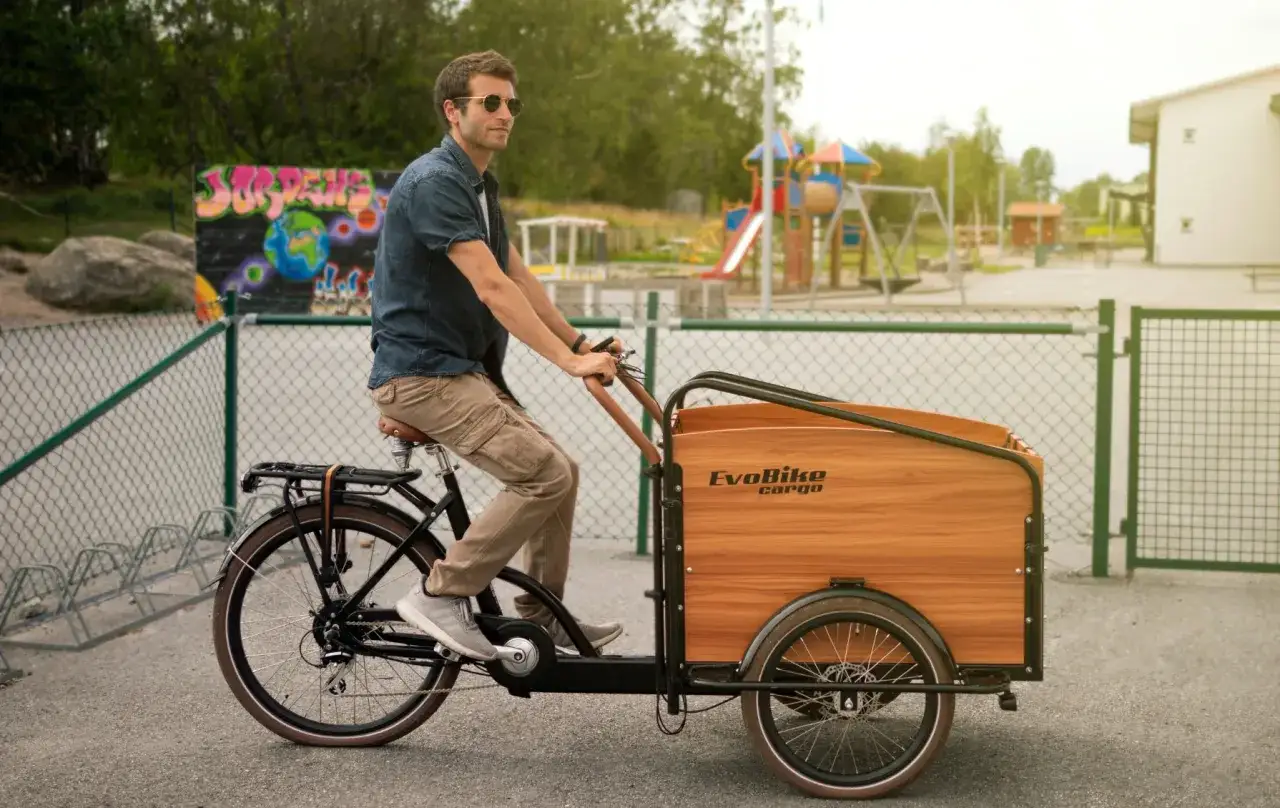 Man cyklar med bebis i en l&aring;dcykel, redo f&ouml;r &auml;ventyr p&aring; lekplatsen.
