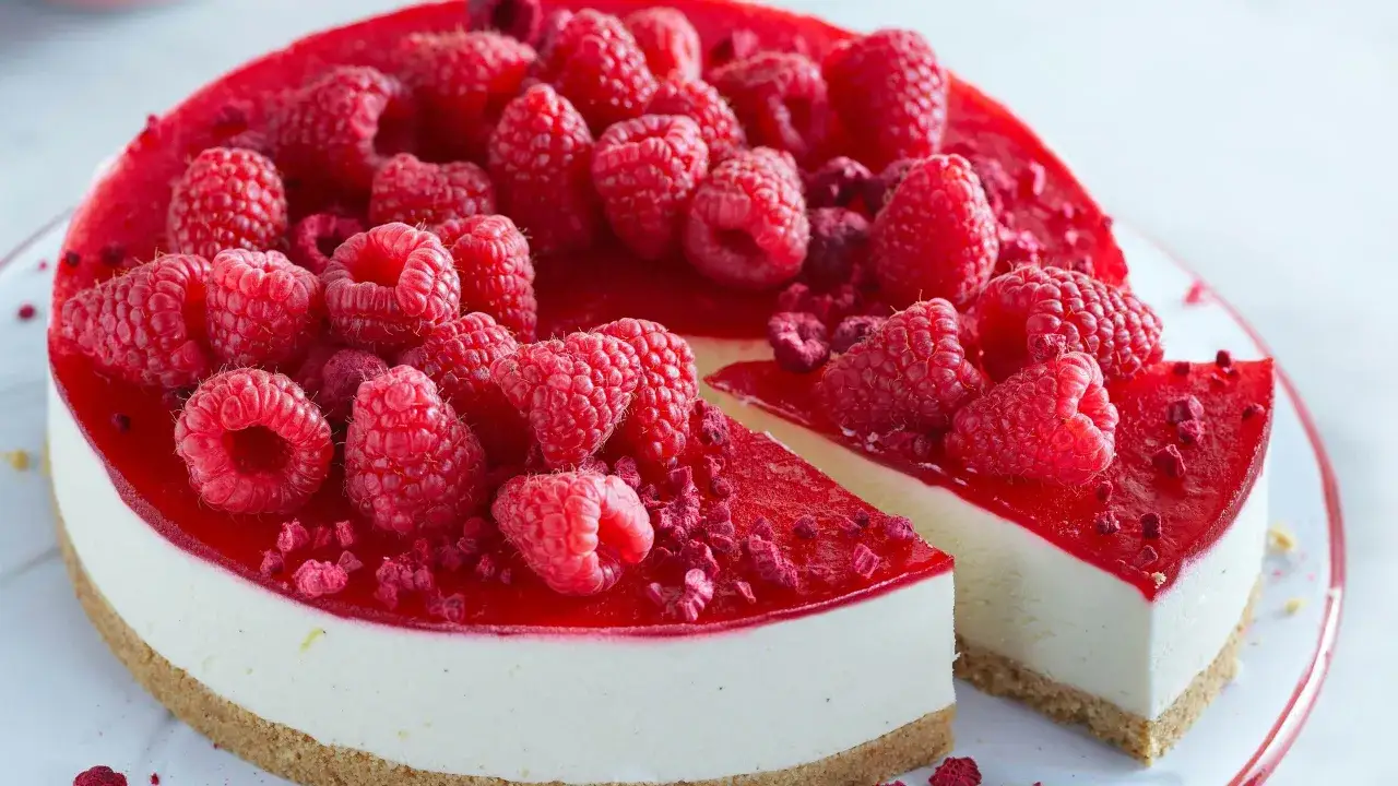 Hallon cheesecake med en krispig botten, toppad med f&auml;rska hallon och hallonspegel. Perfekt hallon recept f&ouml;r sommaren!