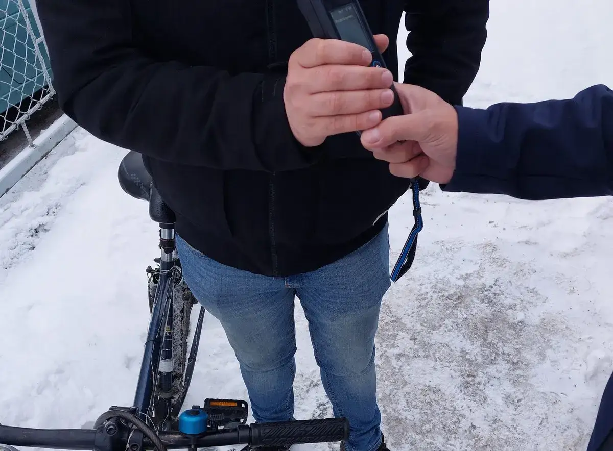 Policjant wręcza rowerzyście urządzenie do pomiaru trzeźwości. Grozi mu mandat za jazdę rowerem po alkoholu.